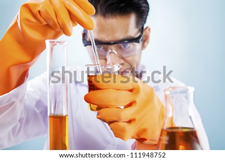 Asian scientist mixing chemicals shot in studio against blue background