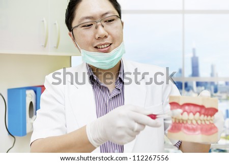 Portrait of male dentist giving direction the right way to brush teeth