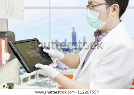 Male dentist pointing at computer tablet to show dental x-ray. shot at the office