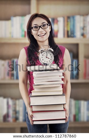 Exams time concept: college student prepares a pile of textbooks and alarm clock for preparing exams