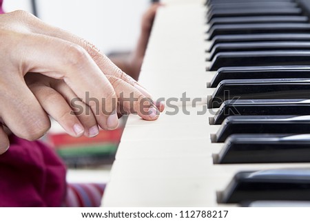 Closeup of hand guiding little piano player playing the piano in the musical class