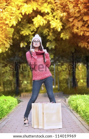 Portrait of young girl with shopping bag posing in autumn park. shot outdoor during autumn