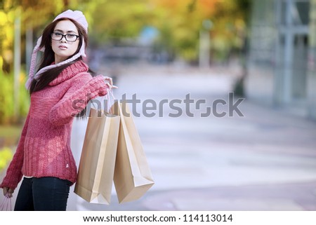 Portrait of young girl carrying shopping bag and dressed for winter time with hat on her head.