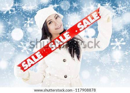 Portrait of fashionable woman showing banner of winter sale. isolated on white background