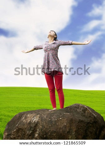Young girl spreading hands with joy and inspiration facing the sky