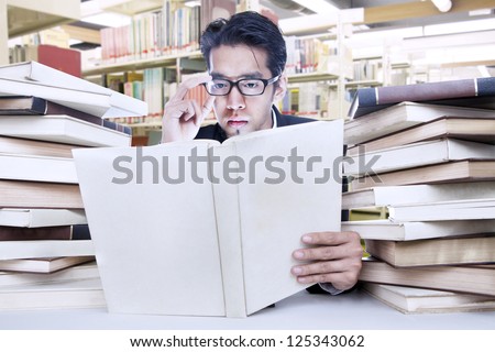 Young businessman is busy reading a book at the library