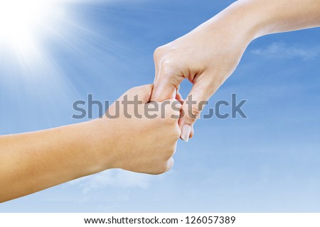 Giving a helping hand. Picture of a mother and son holding hands under blue sky.