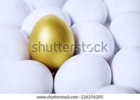 Standing golden egg in between white eggs