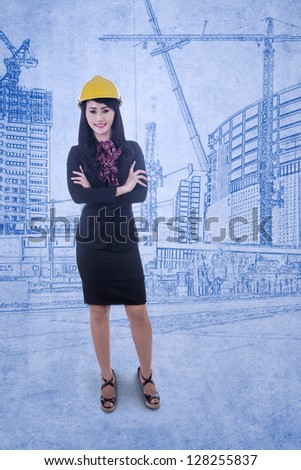 Beautiful architect standing in front of blueprint background