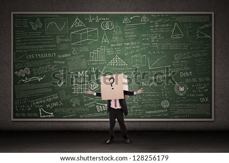 Business person with question mark in front of blackboard