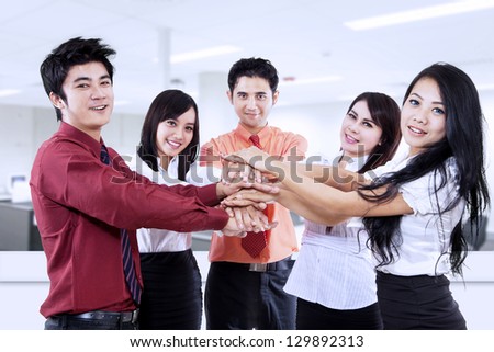 Business team joining their hands in the office
