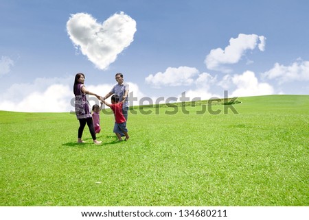 Happy family enjoying valentine\'s day in the park under heart shape clouds