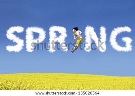 Beautiful asian woman jumping on the canola field with flower