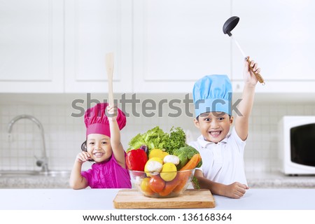 Two Asian cheerful chef kids in kitchen