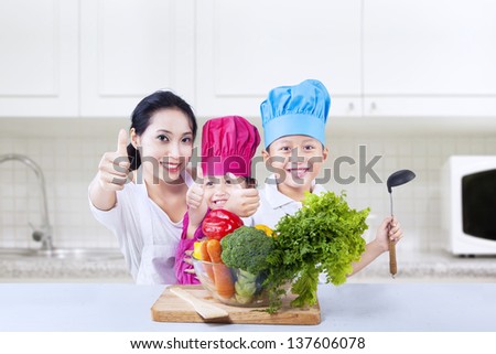 Chef vegetarian kids and mom give thumbs up at their kitchen home