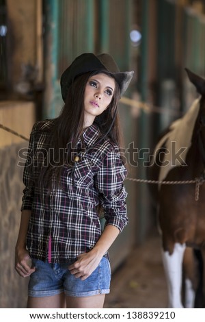 Beautiful Caucasian cowboy girl posing in front of stable