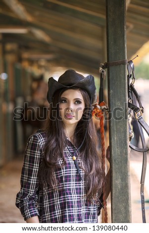 Attractive young woman with cowboy hat at horse ranch