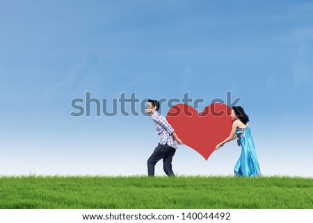 Couple bring heart card on green field outdoor