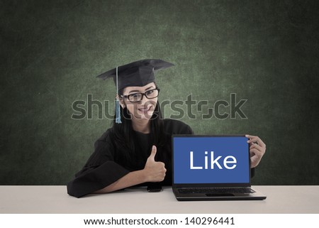 Asian graduate in graduation gown show like on laptop screen