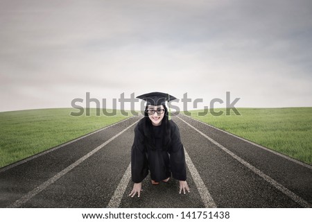 Asian graduate wearing graduation gown ready to race outdoor