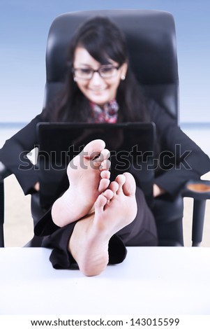 Happy businesswoman relaxing at beach using laptop
