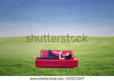 Young woman using tablet outdoor laying on red couch