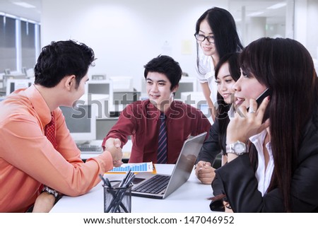 Business manager congratulate his partner while one woman calling at the office