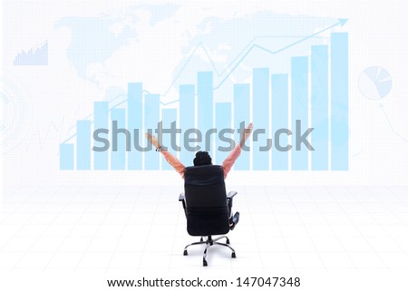Business CEO sitting on a chair with his arms raised looking at profitable bar chart on world map