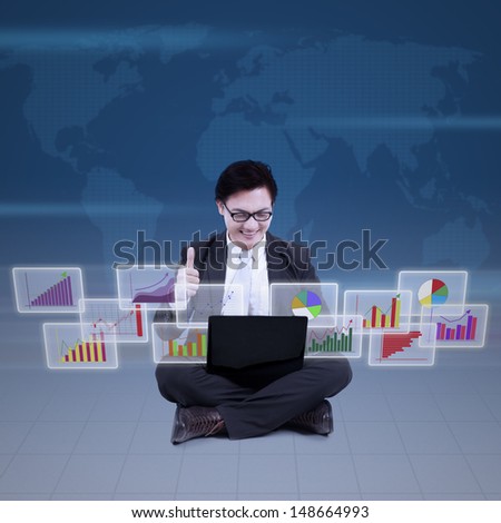 Success businessman using laptop while showing thumbs-up with bar charts presentation