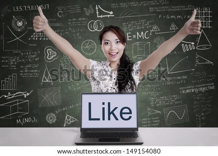 Successful businesswoman giving thumbs-up with laptop computer