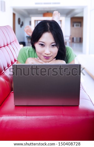Beautiful woman is surfing internet on the laptop at home