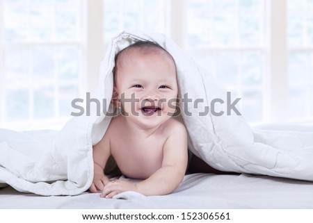 Sad baby boy under blanket at home