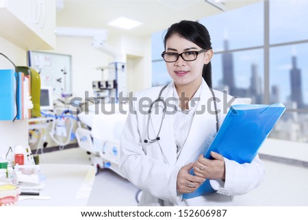 Happy and beautiful female doctor at the hospital with blue folder