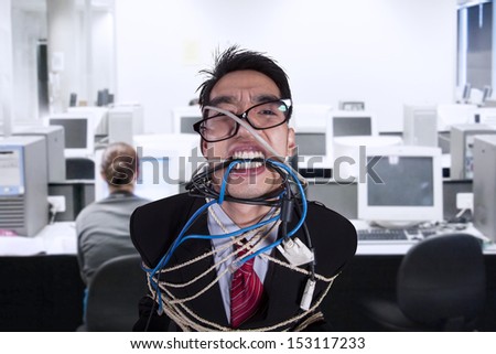 Close-up angry businessman tied in rope and cable at office