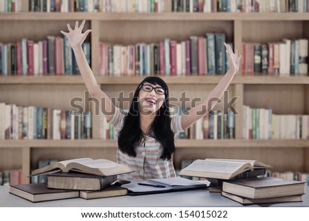 Excited female student with arm raised at library