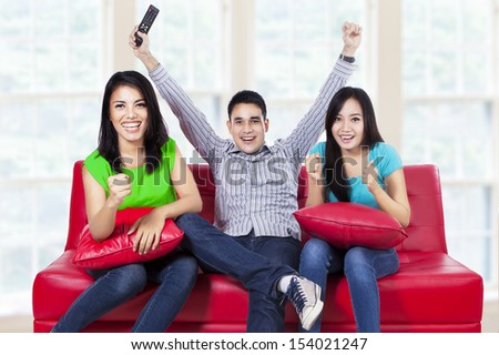 Happy young teenager watching football on tv at home