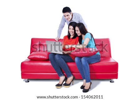 A group of college friends with laptop and sitting on red sofa