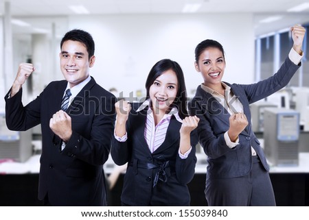 Successful business people celebrating a triumph with arms up at the office