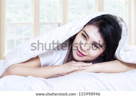 Happy asian girl smiling under a blanket