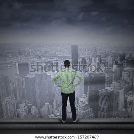 Portrait of a young man looking into the future standing on the top of a skyscraper