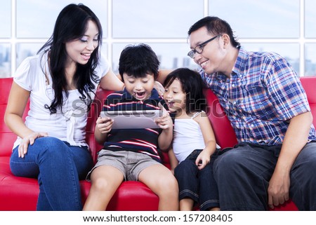 Excited family playing game with e-tablet at apartment i