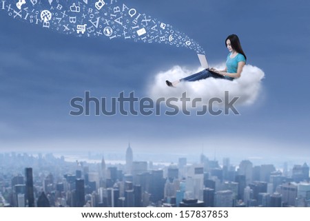 Beautiful asian female student is sending email message using laptop on cloud
