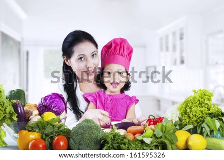 Happy mother and daughter cooking vegetable salad together