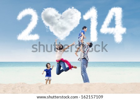 Happy family having fun in the beach with heart shaped cloud of new year 2014 Happy family having fun in the beach with heart shaped cloud of new year 2014
