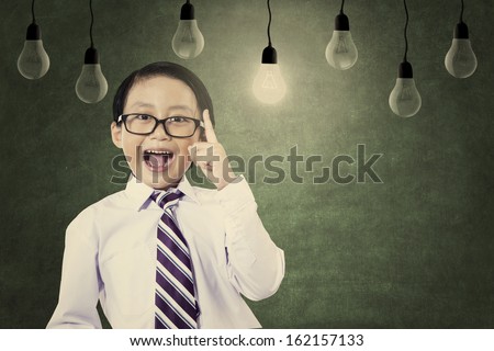 Asian schoolboy raising his hand to convey his idea with lightbulbs above his head