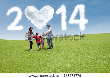Happy asian family playing on the field. They are running in circle shot over blue sky