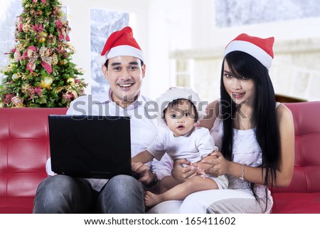 Smiling christmas family using a notebook at home
