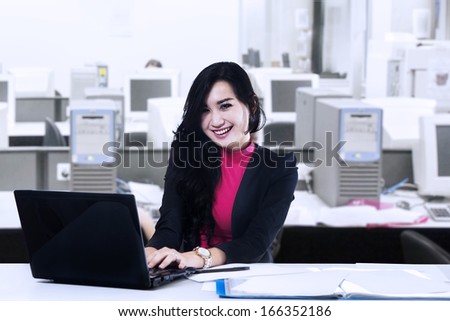 Happy business woman working on laptop computer at office