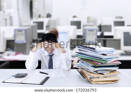 Worried young businessman looking down at documents in office