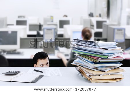 Young businessman looking at stack of papers on the desk
